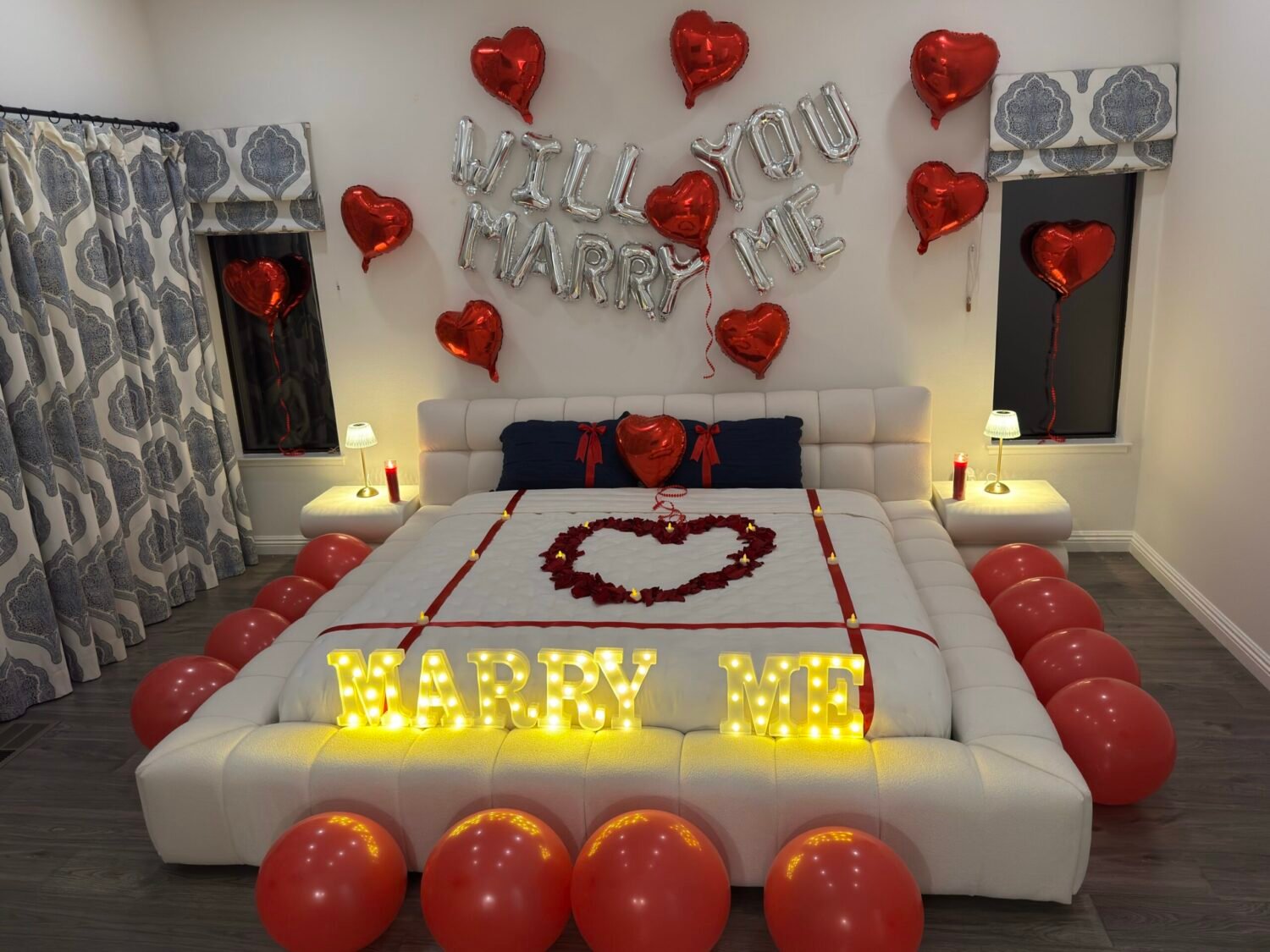 Airbnb proposal setup in Napa Valley with "Will You Marry Me" balloons, heart balloons, "Marry Me" light up letters and rose petals