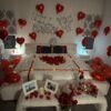 Proposal room setup in San Jose with with "Will You Marry Me" balloons, heart-shaped fresh rose petals, curated champagne, framed pictures, and a dozen roses with glass vase
